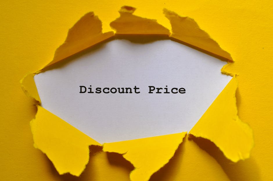 A piece of bright yellow paper is torn open to reveal a white sheet underneath with the words 'Discount Price' printed in black typewriter-style font. The torn edges of the yellow paper are irregular 